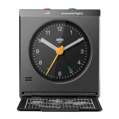 Bild av Braun klassisk analog reseväckarklocka med snooze och ljus, ikonisk design, kompakt storlek, vikbart lock världskarta, tyst kvartsrörelse, Crescendo pip alarm i svart, modell BC05B